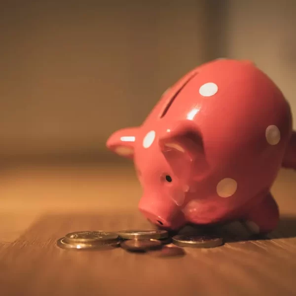 a close up shot of a piggy bank besides coins