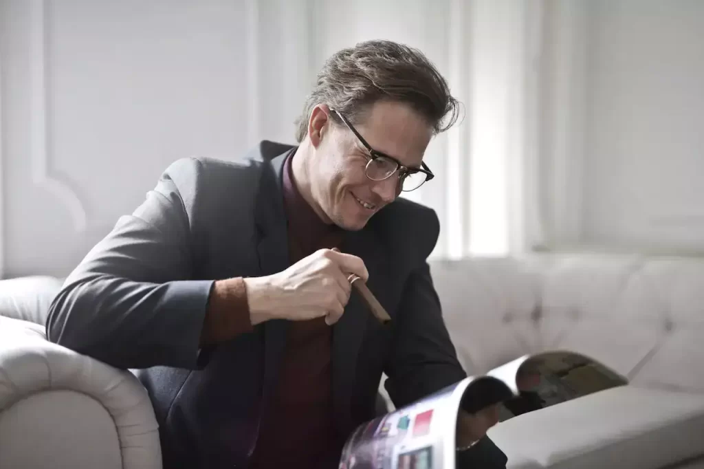 Elegant businessman with a cigar reading a magzine at home