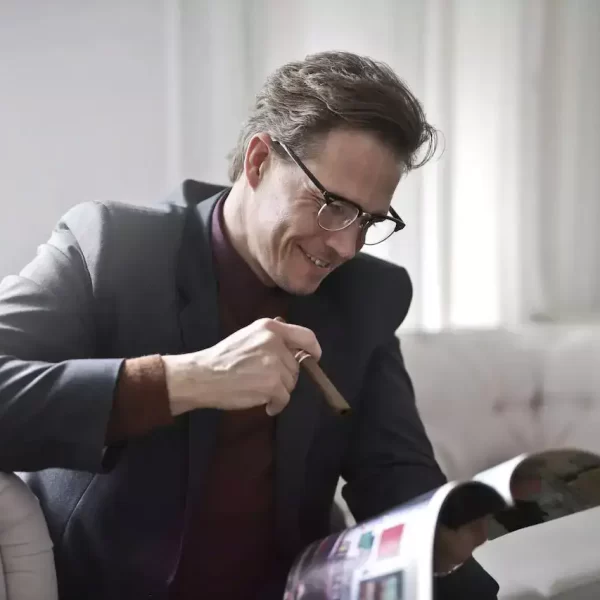 Elegant businessman with a cigar reading a magzine at home