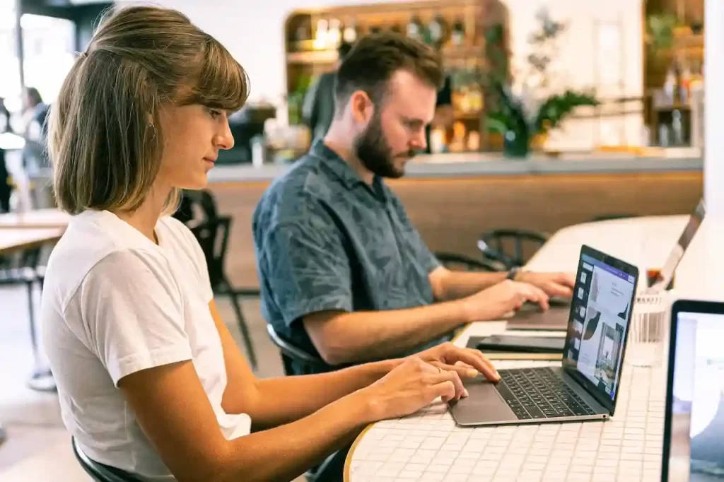 A man and a woman sitting together and working on their laptops