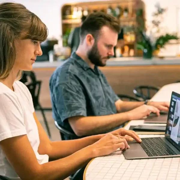 A man and a woman sitting together and working on their laptops