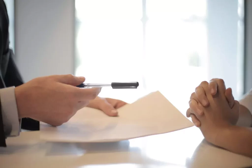 A business man giving a pen to sign a contract