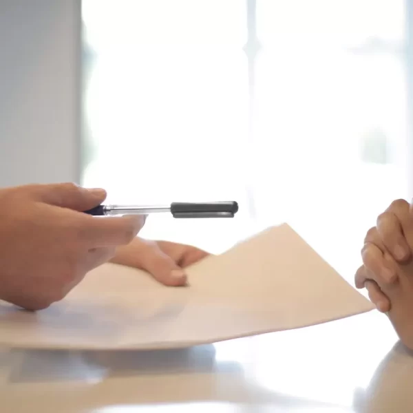 A business man giving a pen to sign a contract