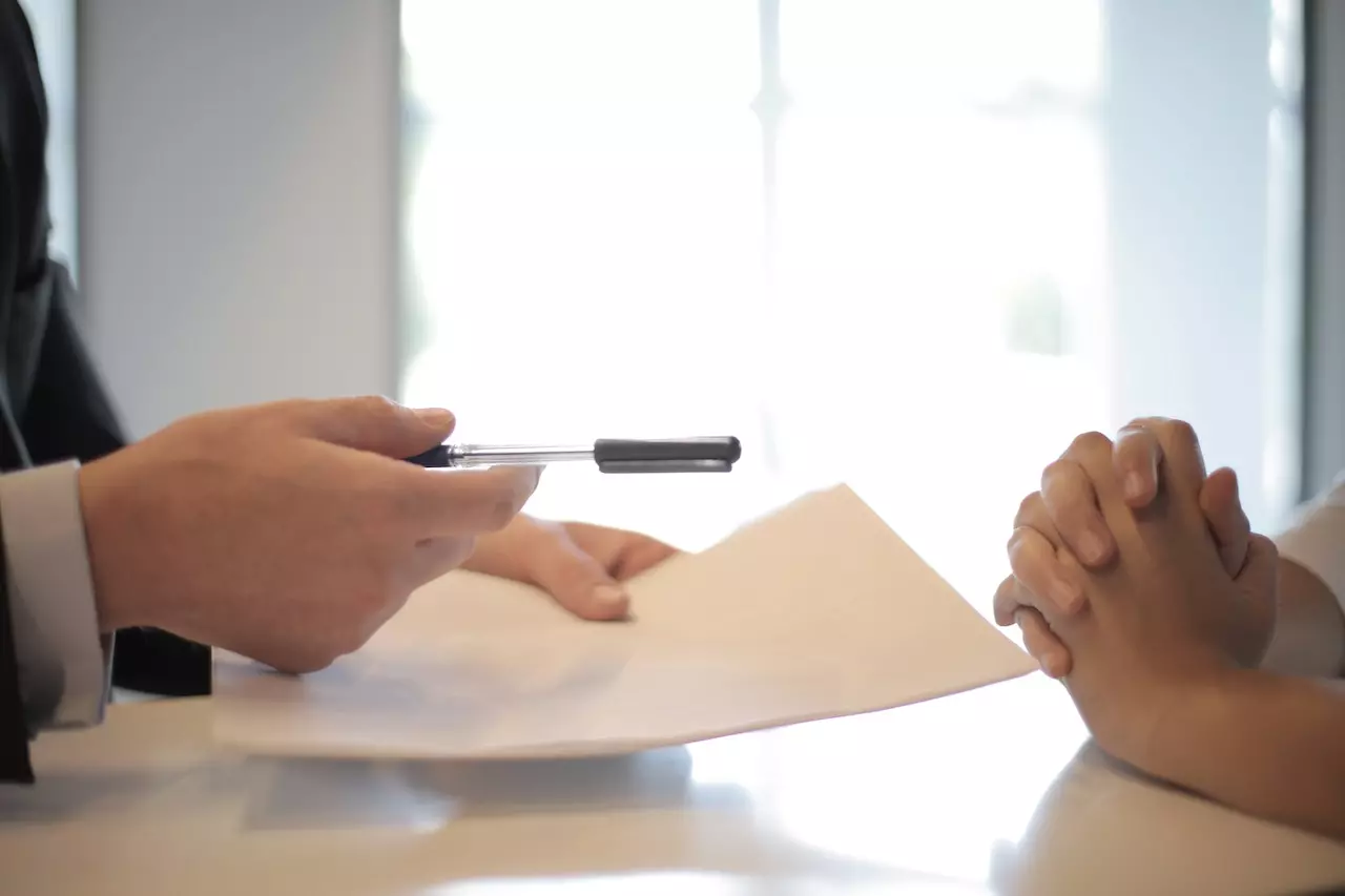 A business man giving a pen to sign a contract