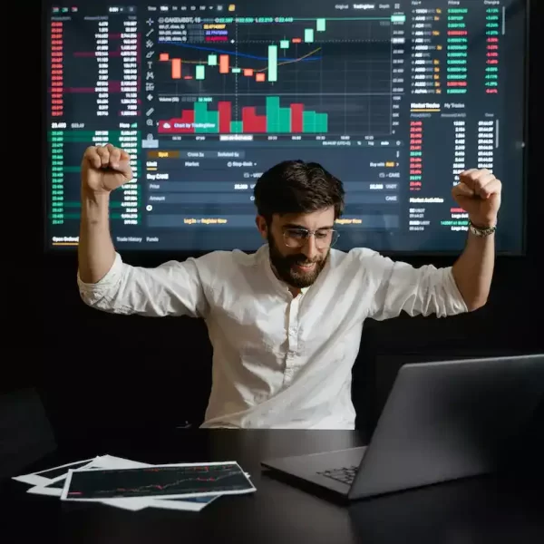 A man raising his hands for being being successful with a trading chart projected behind him