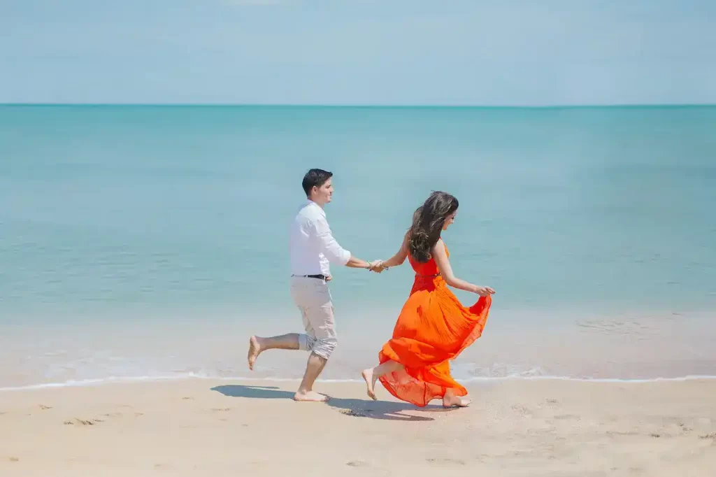 Man and Woman walk beside green sea