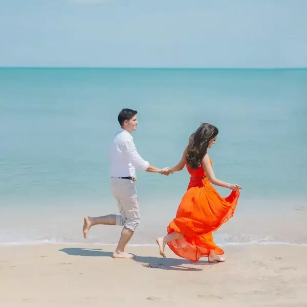 Man and Woman walk beside green sea