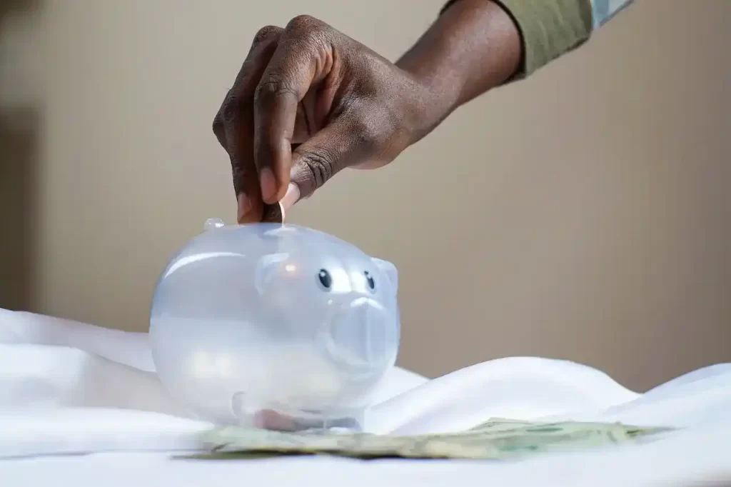 A person putting a coin in a piggy bank