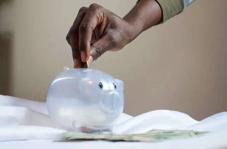 A person putting a coin in a piggy bank