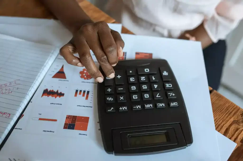 A person using a black calculator on a desk