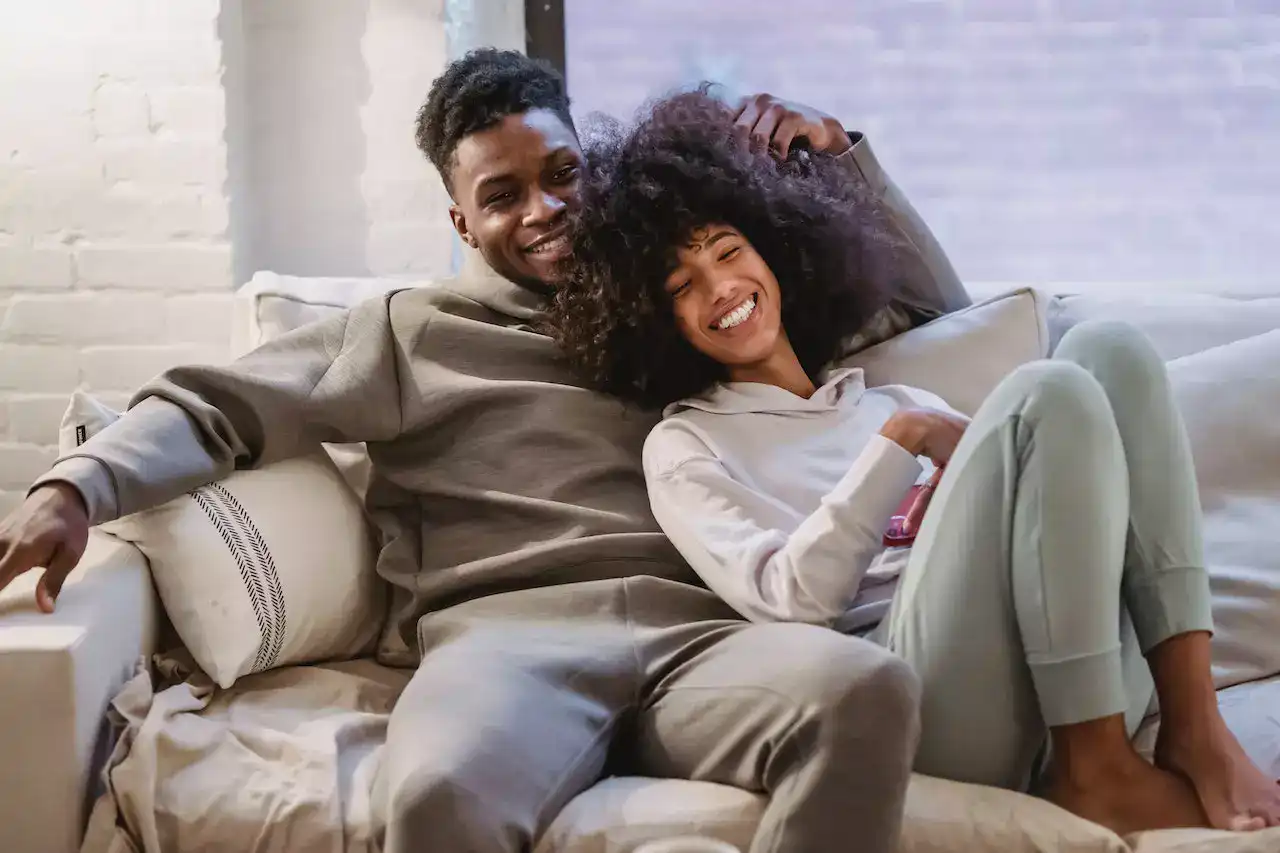 A black American couple cuddling on the couch