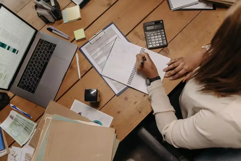 A person holding papers on a table and signing them