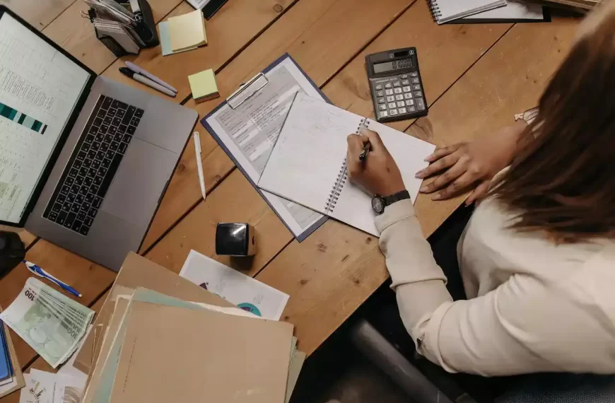 A person holding papers on a table and signing them