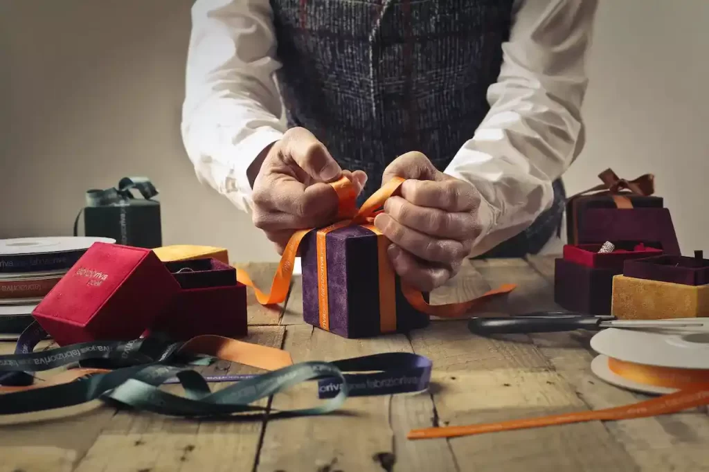 A person tying ribbon on a purple gift box