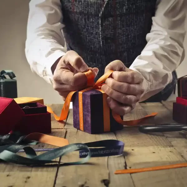 A person tying ribbon on a purple gift box