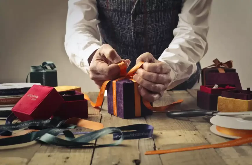 A person tying ribbon on a purple gift box