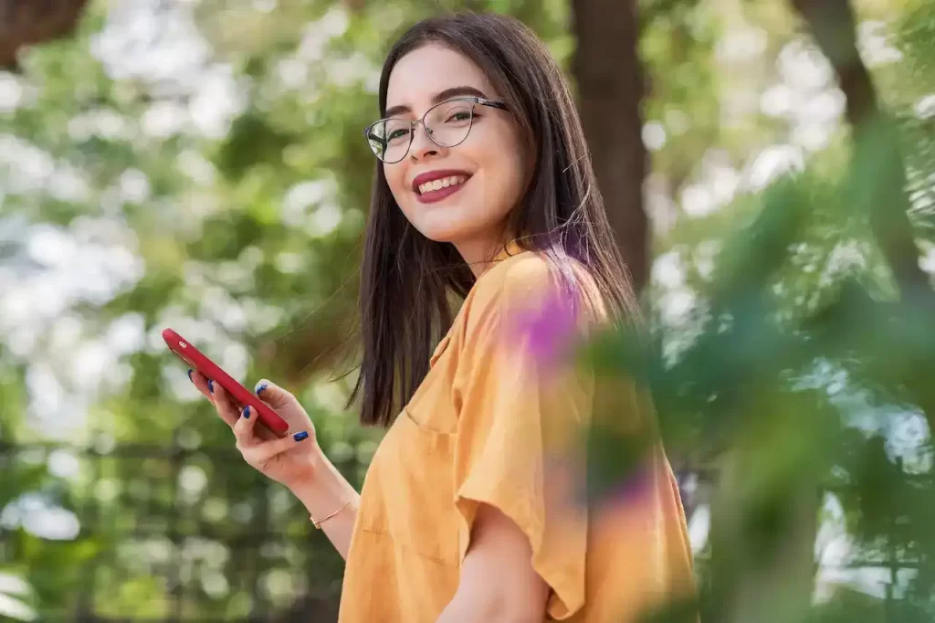 Smiling girl wearing eyeglasses with a phone in her hand