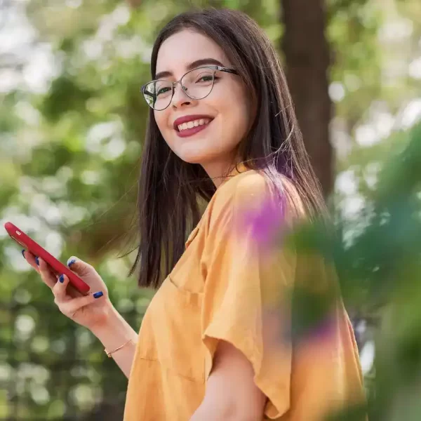 Smiling girl wearing eyeglasses with a phone in her hand