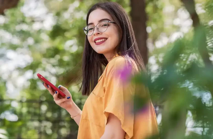 Smiling girl wearing eyeglasses with a phone in her hand