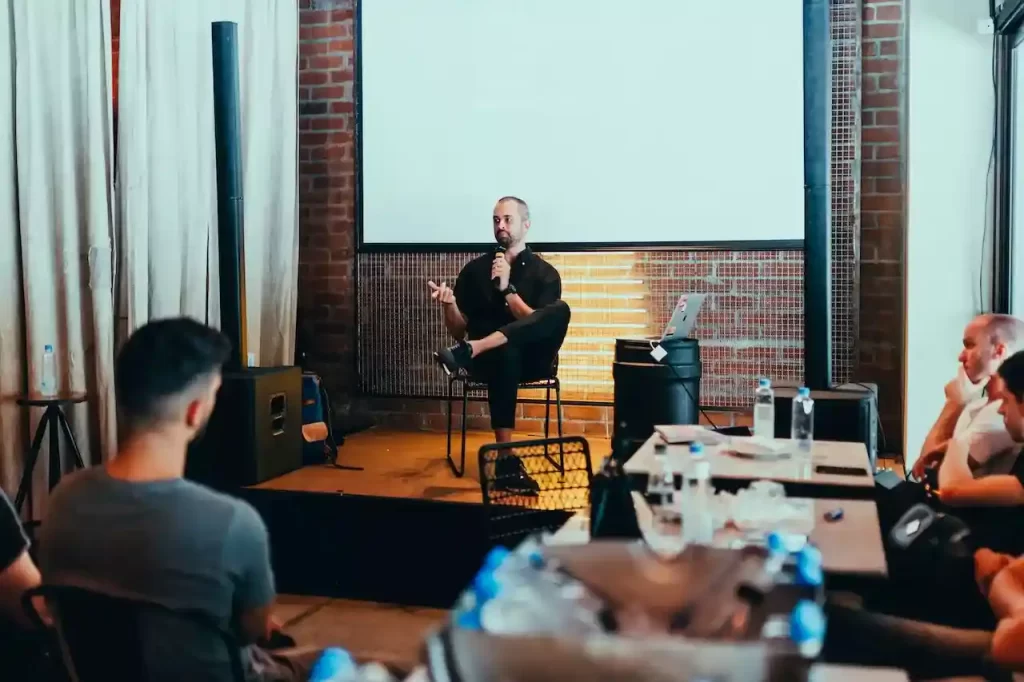 A man holding a mic and talking on stage