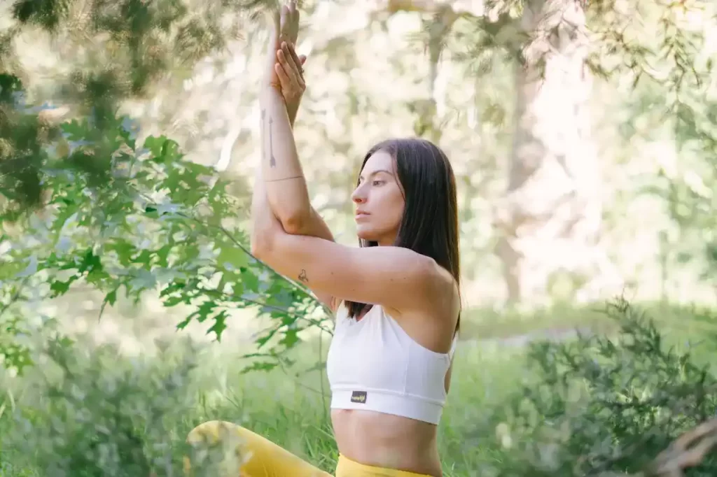 A woman doing yoga around plants