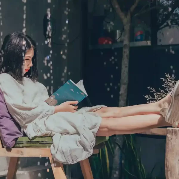 a sitting on a chair with her feet on the table, reading a book