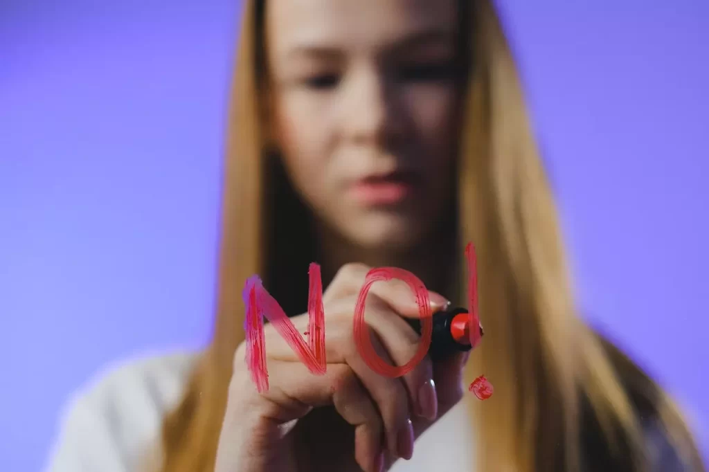 An out of focus girl writing "NO" on a glass